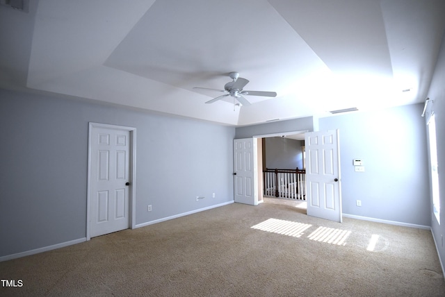 unfurnished room featuring light carpet, ceiling fan, and a tray ceiling