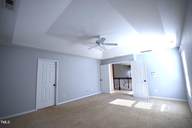 spare room featuring light carpet, ceiling fan, and a tray ceiling