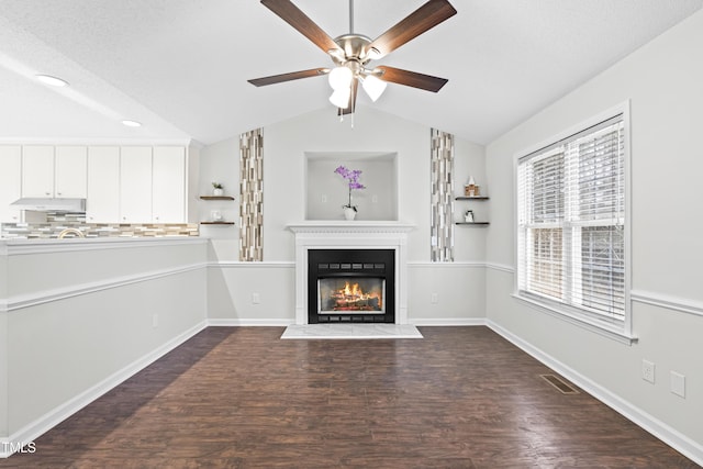 unfurnished living room featuring vaulted ceiling, dark wood-type flooring, and ceiling fan