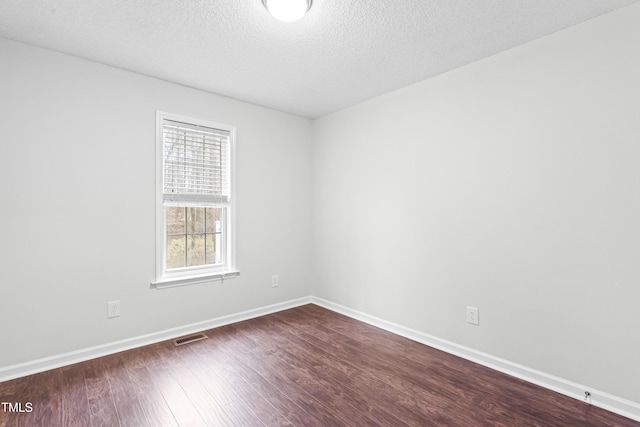 spare room featuring dark hardwood / wood-style flooring and a textured ceiling