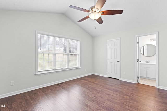 unfurnished bedroom featuring lofted ceiling, ensuite bath, dark hardwood / wood-style flooring, sink, and ceiling fan