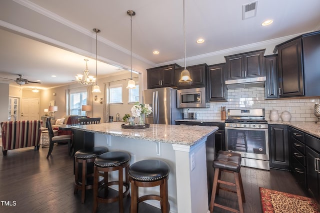 kitchen with hanging light fixtures, decorative backsplash, stainless steel appliances, and a center island