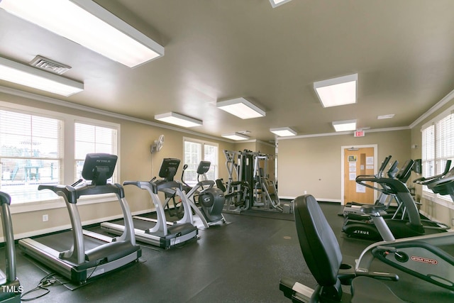 exercise room with baseboards, visible vents, and crown molding