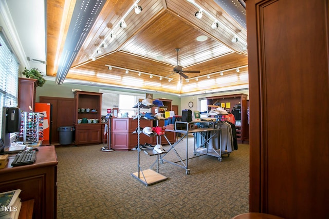 workout area featuring wood ceiling, dark colored carpet, a raised ceiling, ceiling fan, and crown molding