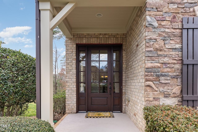 property entrance with stone siding and brick siding