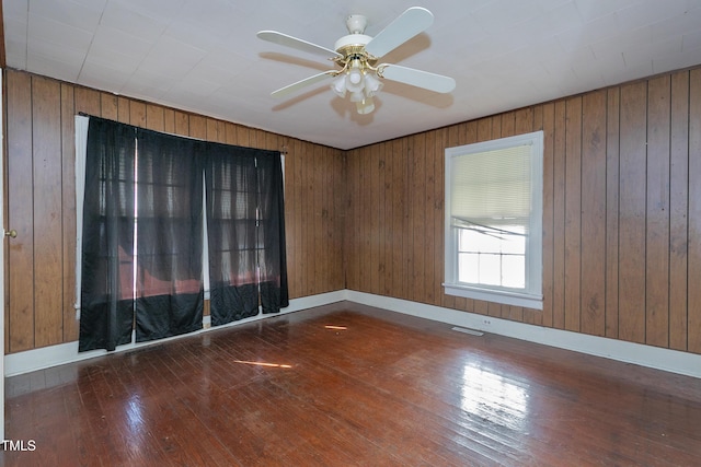 unfurnished room with ceiling fan, dark hardwood / wood-style flooring, and wooden walls