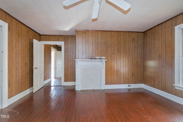 spare room featuring ceiling fan, wood-type flooring, and wood walls