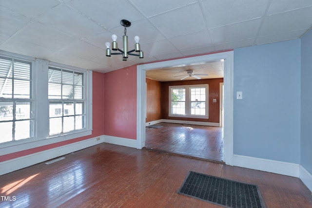 unfurnished dining area featuring dark wood-type flooring, a paneled ceiling, and ceiling fan with notable chandelier