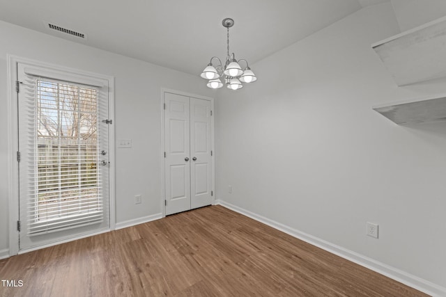 unfurnished dining area featuring a healthy amount of sunlight, an inviting chandelier, hardwood / wood-style floors, and lofted ceiling