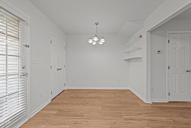 unfurnished dining area with a wealth of natural light, light hardwood / wood-style flooring, and a notable chandelier