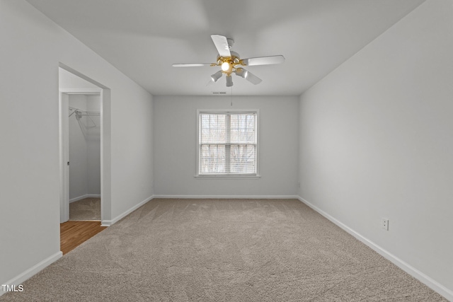 unfurnished bedroom with a closet, ceiling fan, carpet, and a spacious closet