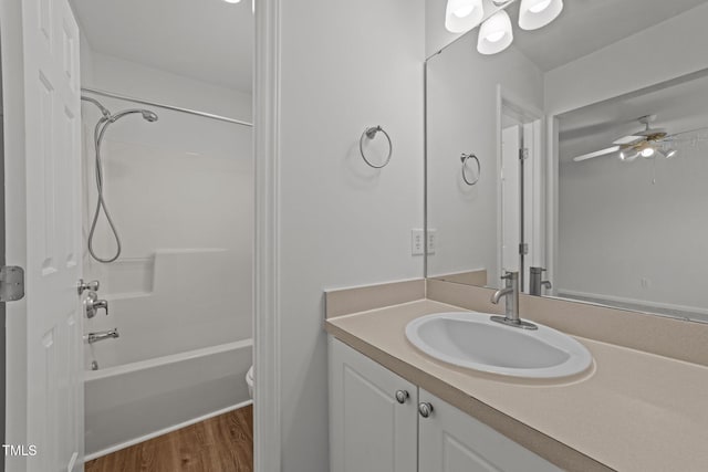 full bathroom featuring ceiling fan, hardwood / wood-style flooring, toilet, shower / tub combination, and vanity