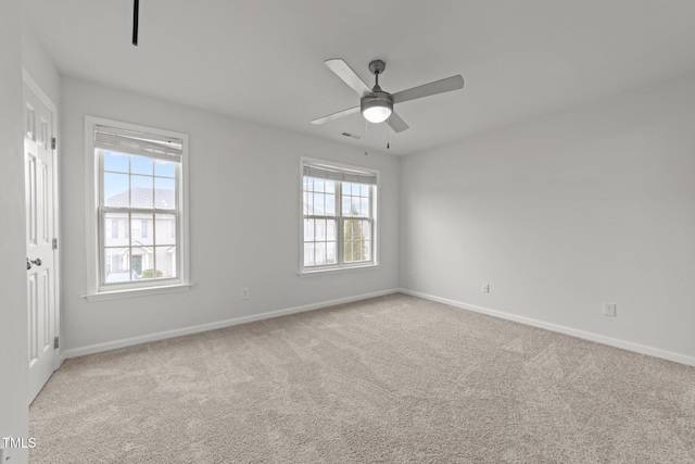 spare room with ceiling fan, a wealth of natural light, and light carpet