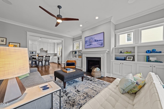 living room featuring crown molding, plenty of natural light, ceiling fan, and dark hardwood / wood-style flooring