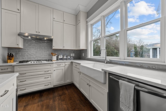 kitchen featuring stainless steel appliances, white cabinetry, light stone counters, and decorative backsplash