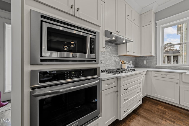 kitchen featuring white cabinetry, appliances with stainless steel finishes, dark hardwood / wood-style floors, and backsplash