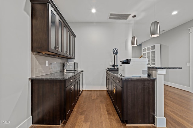 kitchen with dark brown cabinets, pendant lighting, and dark stone counters