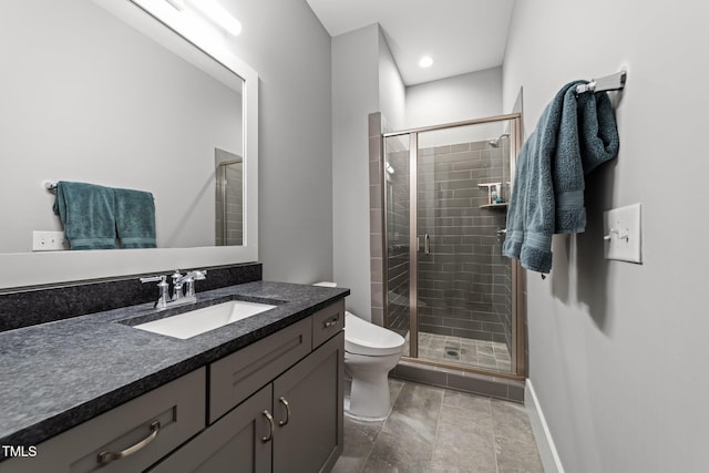 bathroom featuring toilet, vanity, and a shower with shower door