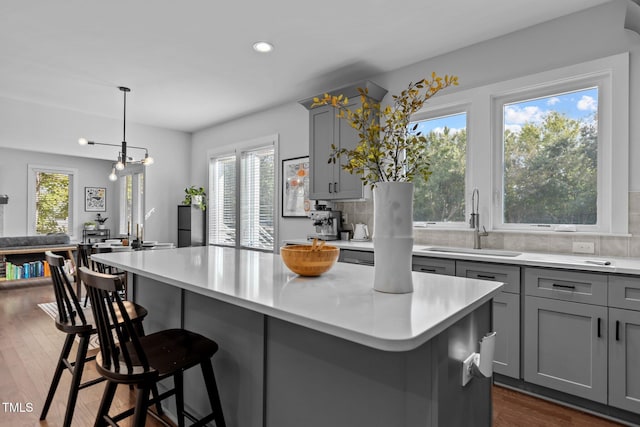 kitchen with decorative light fixtures, decorative backsplash, gray cabinetry, and a center island