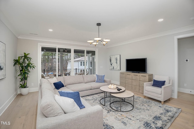 living room featuring an inviting chandelier, ornamental molding, and light hardwood / wood-style floors