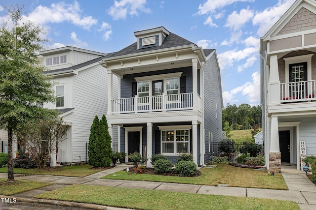 view of front of home featuring a front lawn, covered porch, and a balcony