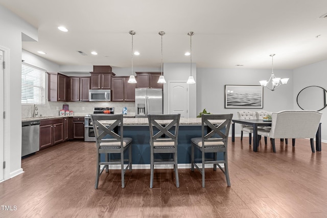 kitchen with stainless steel appliances, hanging light fixtures, a center island, and backsplash