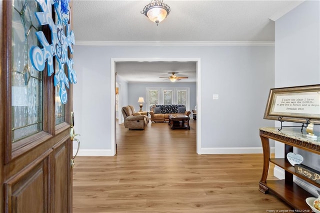 foyer featuring ceiling fan, light wood-type flooring, crown molding, and a textured ceiling