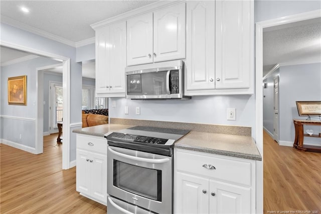 kitchen with white cabinetry, appliances with stainless steel finishes, light hardwood / wood-style flooring, and ornamental molding