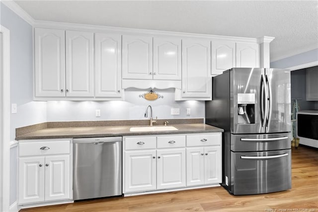 kitchen with light wood-type flooring, appliances with stainless steel finishes, sink, and white cabinetry