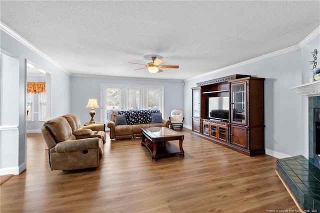 living room with ceiling fan, ornamental molding, hardwood / wood-style floors, and a tile fireplace