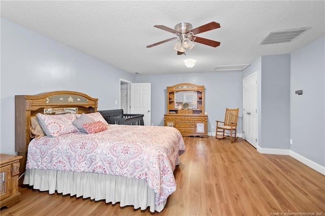 bedroom with a textured ceiling, ceiling fan, a closet, and hardwood / wood-style flooring