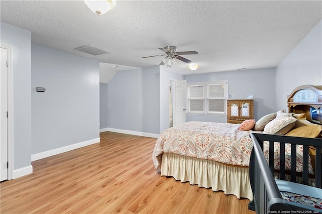 bedroom with ceiling fan, a textured ceiling, and light hardwood / wood-style flooring