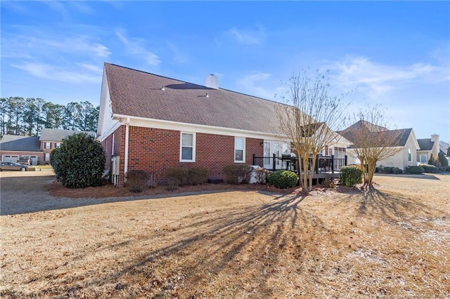 back of property with a wooden deck and a yard