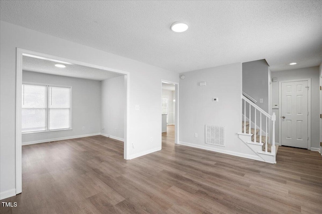 unfurnished living room with hardwood / wood-style flooring and a textured ceiling