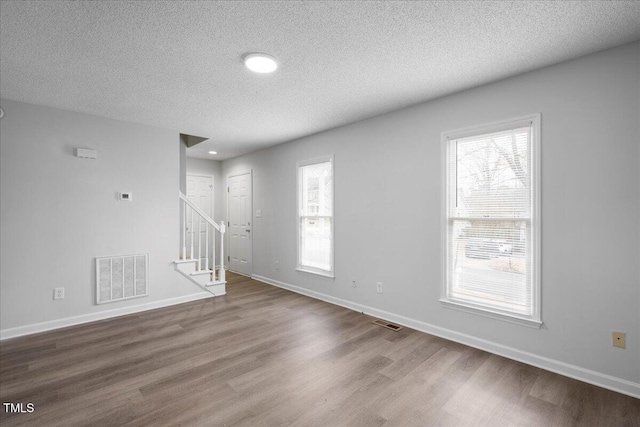 empty room featuring wood-type flooring and a textured ceiling