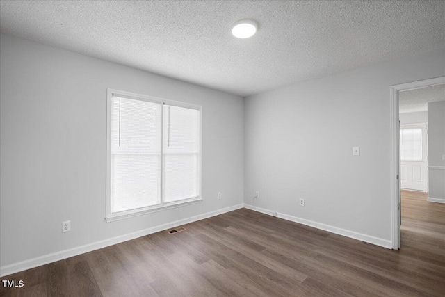 unfurnished room with dark hardwood / wood-style flooring, plenty of natural light, and a textured ceiling