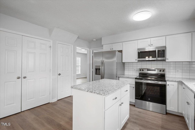 kitchen featuring stainless steel appliances, a center island, light wood-type flooring, and white cabinets