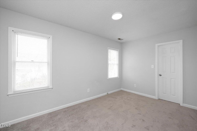 carpeted empty room with a textured ceiling