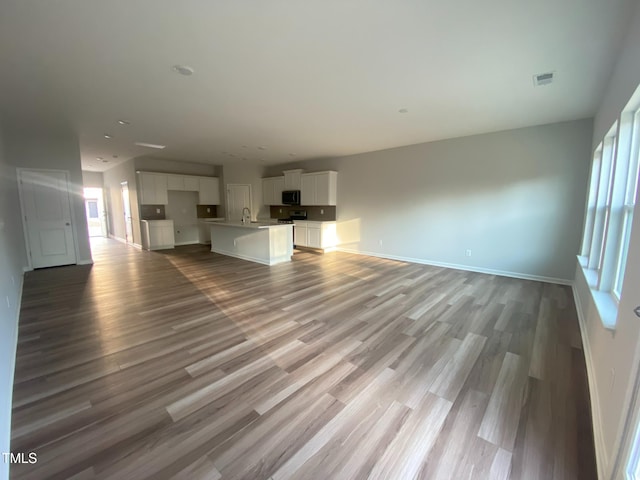 unfurnished living room featuring sink and light hardwood / wood-style floors