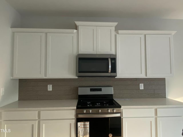 kitchen featuring decorative backsplash, white cabinets, and appliances with stainless steel finishes