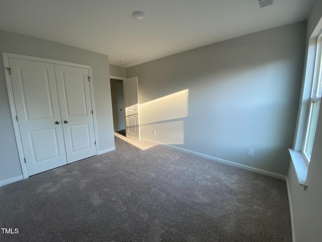 unfurnished bedroom featuring a closet and dark colored carpet