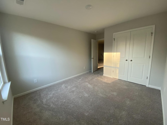 unfurnished bedroom with a closet and dark colored carpet