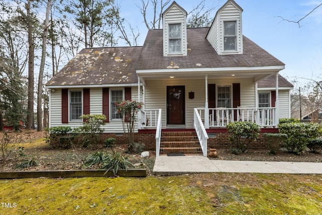 cape cod home with a front yard and covered porch