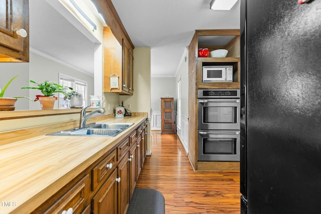 kitchen with crown molding, sink, stainless steel double oven, and black refrigerator