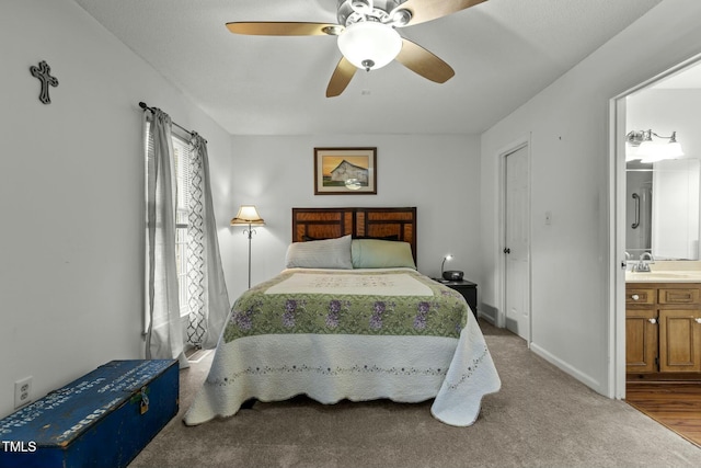 bedroom with multiple windows, sink, light colored carpet, ceiling fan, and ensuite bath