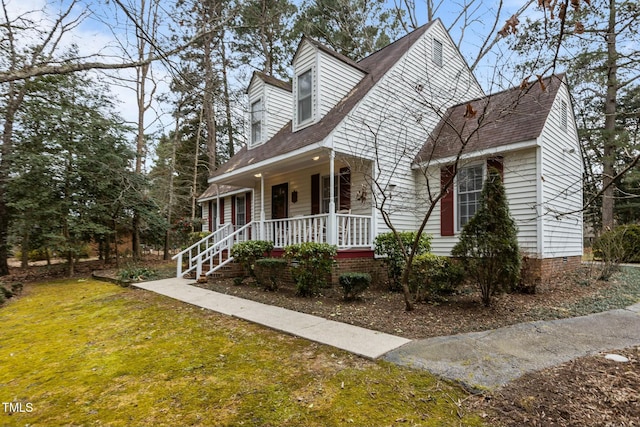 cape cod-style house featuring covered porch and a front lawn