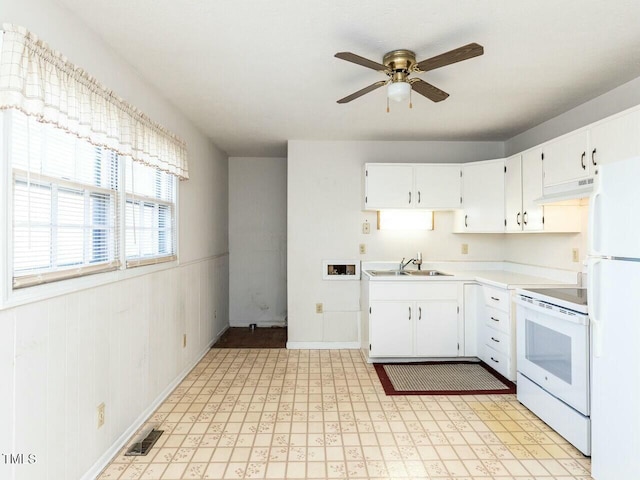 kitchen with sink, white appliances, wooden walls, ceiling fan, and white cabinets