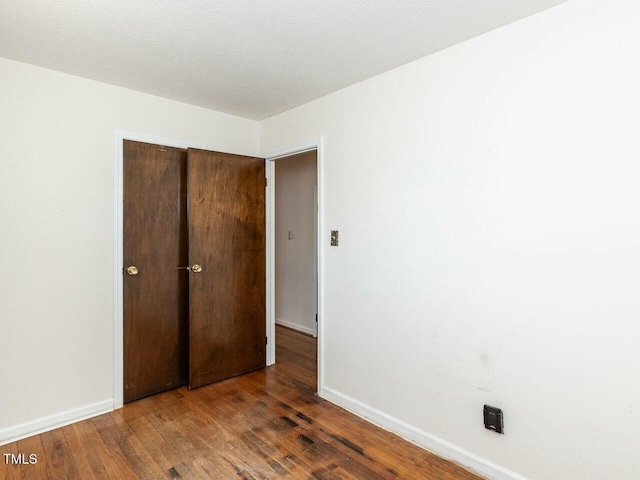 unfurnished bedroom featuring dark hardwood / wood-style flooring and a closet