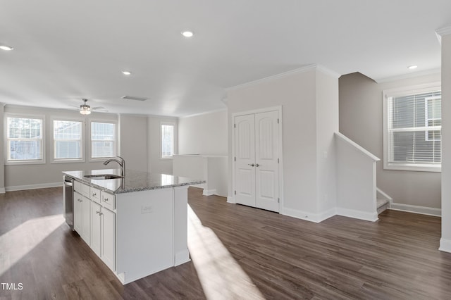 kitchen featuring a kitchen island with sink, stone counters, stainless steel dishwasher, white cabinets, and sink