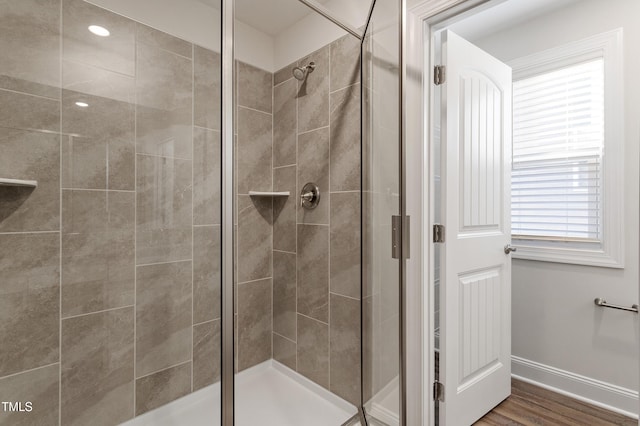 bathroom with a shower with shower door and wood-type flooring